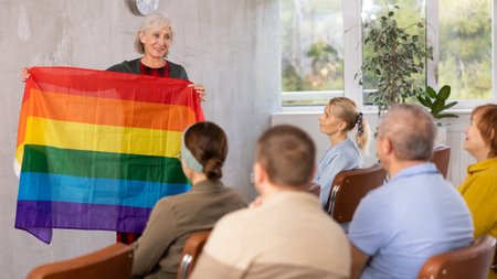 Mature female professor showing rainbow flag to elderly studentsの写真素材