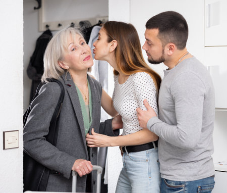 Woman and her husband welcoming senior mother at homeの写真素材
