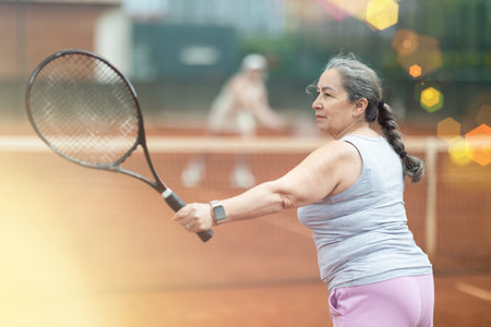 Sporty senior woman playing tennis with female opponent outdoorsの写真素材
