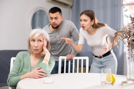 Senior woman ignoring adult couple scolding herの写真素材