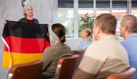 Female tutor showing flag of Germany leading language club for elderlyの写真素材