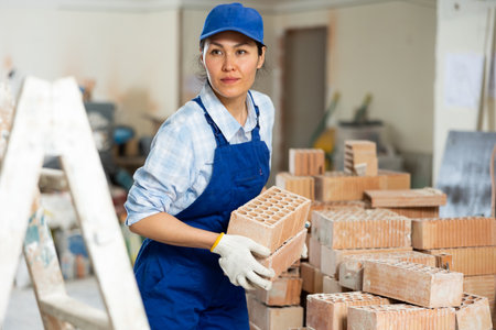 Female builder carrying bricks at renovating objectの写真素材