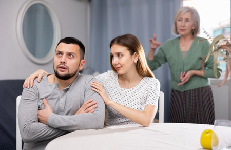 Wife comforting husband after quarrel with elderly mother at homeの写真素材