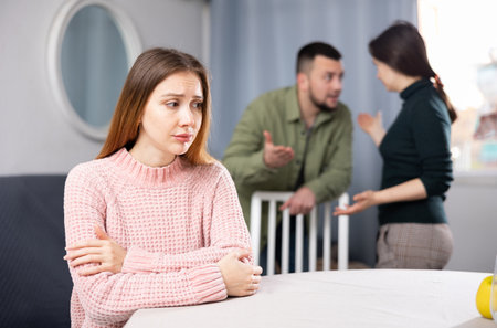 Woman sitting at table while man and woman arguing behind her backの写真素材
