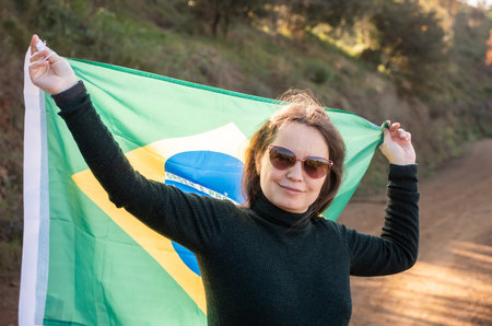 Smiling woman holding large flag of Brazilの写真素材