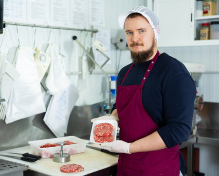 Cooking semi finished products - man shows meat cutlets using special devicesの写真素材