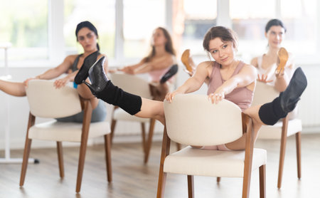 Sitting on chair, girl trains to perform, interacting with imaginary partnerの写真素材
