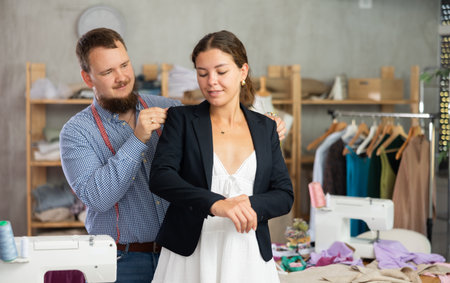 Young girl trying ready jacket with tailors helpの写真素材