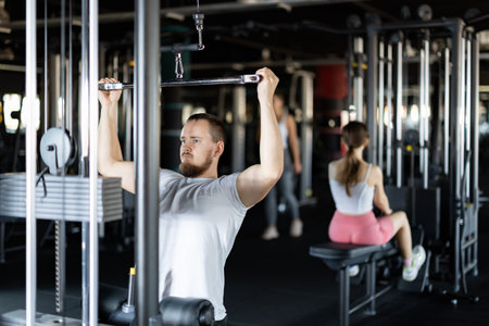 Young athletic man work out muscles of hands on cable crossover machine in fitness clubの写真素材