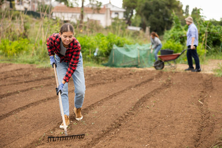 Girl is working in garden with rakeの写真素材