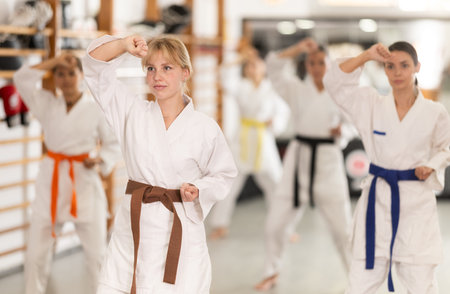 Young woman practicing kata standing in row with othersの写真素材
