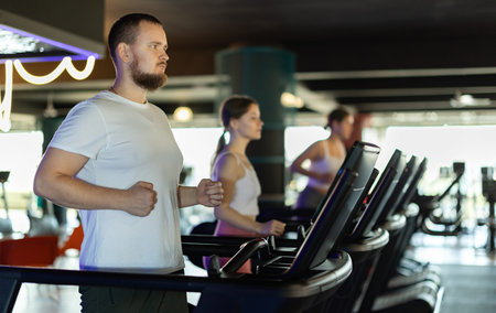 Young man exercising on treadmill in gym