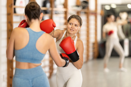 Young girl training boxing with partner during sports classes