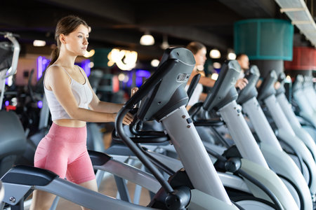 Young woman performs fitness task using an elliptical simulator
