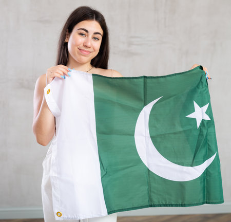 Happy young woman with flag of Pakistan against unicoloured backgroundの写真素材