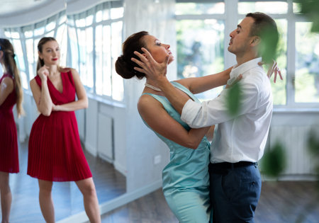 Coach, paired with man student, shows master class and explains technique of tango dance