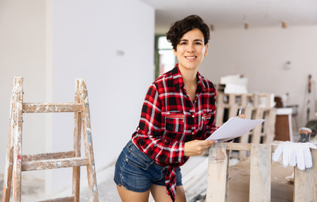 Portrait of woman filling documentation during repair works in construction siteの写真素材