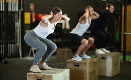 Sportive young girl squatting on box during crossfit workoutの写真素材