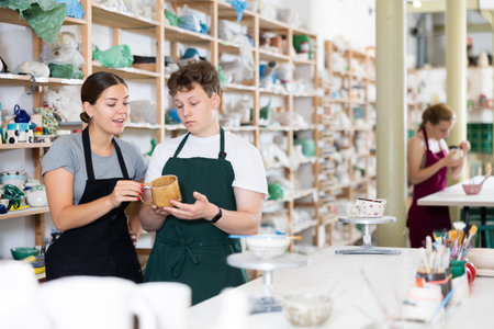Master potter checks clay mug made by young guyの写真素材