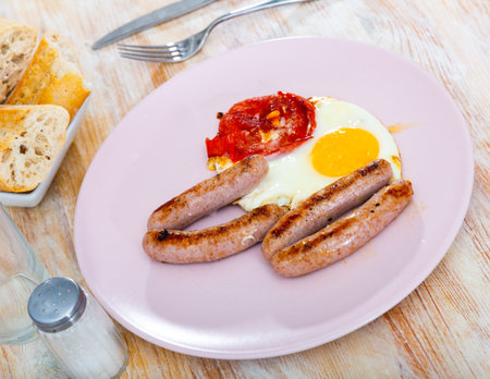 Breakfast of fried eggs with sausage and tomatoesの写真素材