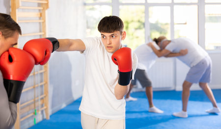 Man and guy at boxing training in gym practice striking techniques. Man put block on blow in his...