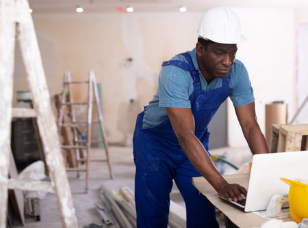 Portrait of a male builder who checks work done using a laptopの写真素材