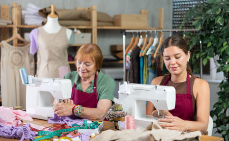 Elderly and young women seamstresses sewing on machine