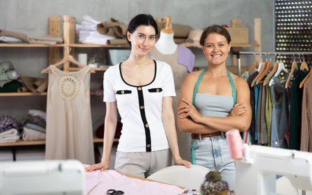 Smiling young professional seamstresses posing in workshop