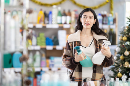 Young woman choosing cleaning spray in store during Christmasの写真素材