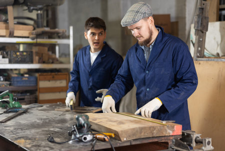 Young man measuring wooden board with tape measureの写真素材