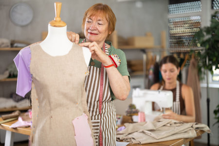 Elderly woman working with mannequin, young woman sewing