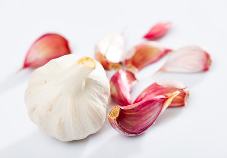 Garlic cloves on white background with kitchen knifeの写真素材