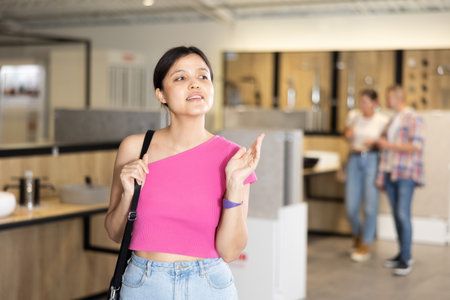 Young Asian female shopper browsing bathroom fixtures in showroomの写真素材