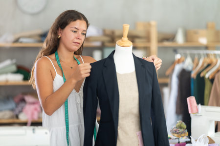 Female tailor fitting black blazer on mannequinの写真素材