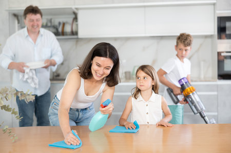 Positive mother and daughter cleaning the surface of kitchen tableの写真素材