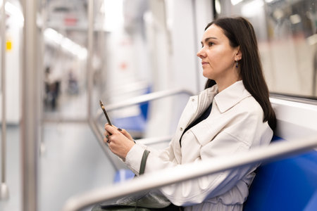 Woman in metro carriage points phone camera at an information board