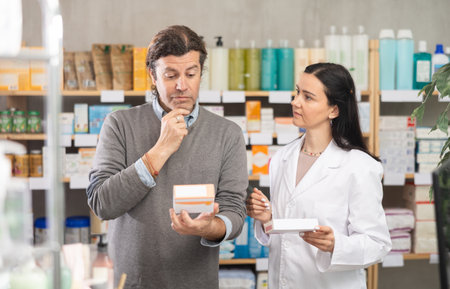 Man chooses pills in modern pharmacy. Female pharmacist helps with choosing medicineの写真素材