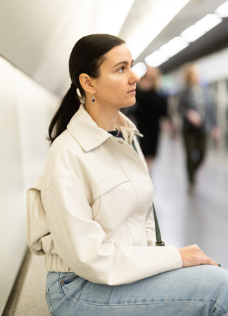 Girl is sitting on metro platform station, waiting for transport to arriveの写真素材