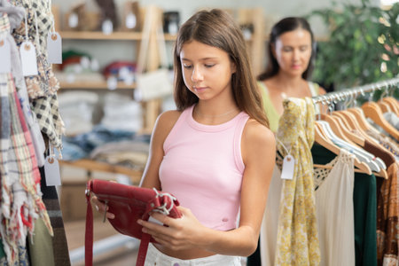 Teenage girl choosing handbag in clothing storeの写真素材