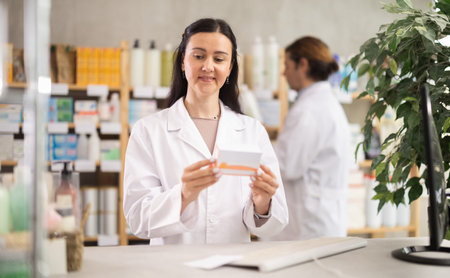 Female pharmacist offering box of pills