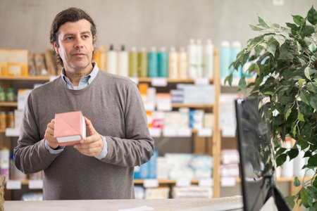 Adult man chooses pills at pharmacyの写真素材