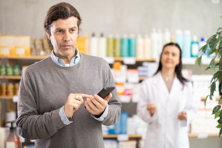 man with a phone in his hands chooses goods in a pharmacyの写真素材