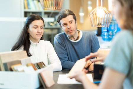 Married couple discusses choice of material - laminate or wood - for their future furniture with furniture store managerの写真素材