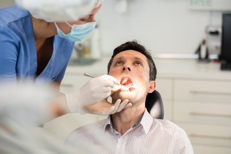Young female dentist examining male patientの写真素材