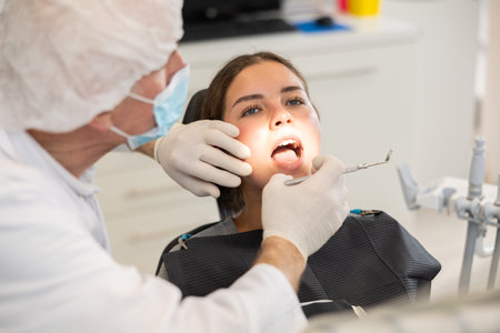 Elderly male dentist examining female patientの写真素材