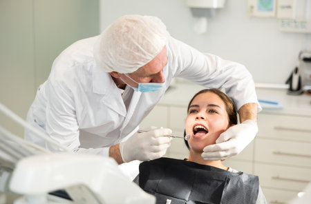 Elderly male dentist examining female patientの写真素材
