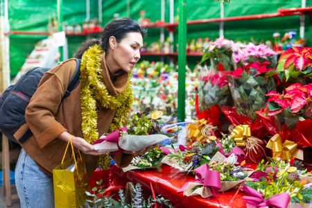Asian female purchasing christmas bouquet at fairの写真素材