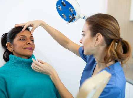 Beautician examining face skin of female patient