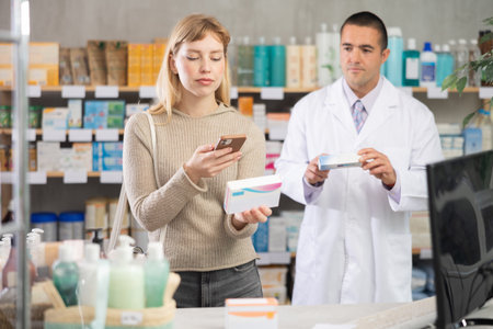 Young woman in pharmacy scans QR code on probiotic pills, man pharmacist in backgroundの写真素材