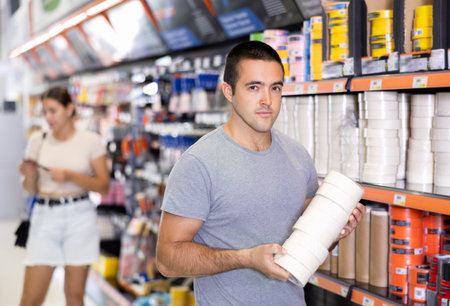 Man buy sticky adhesive tape in construction store for carrying out internal finishing workの写真素材
